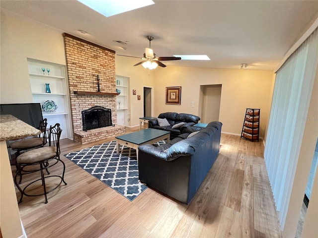 3907 Applegate Cir, Brandon, FL 33511 - living area with a skylight, light wood-style floors, a brick fireplace, a ceiling fan, and built in shelves