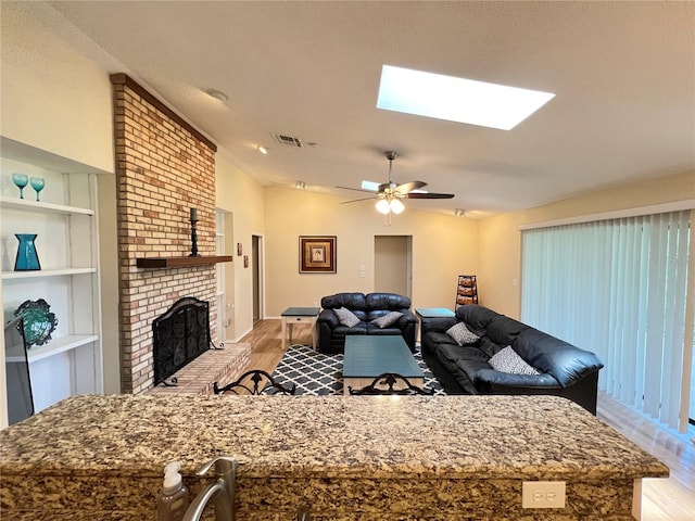 3907 Applegate Cir, Brandon, FL 33511 - living area featuring light wood-type flooring, a skylight, ceiling fan, a brick fireplace, and vaulted ceiling