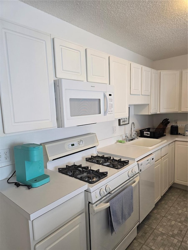 kitchen with light countertops, white appliances, a textured ceiling, and a sink