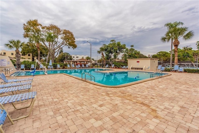 community pool with a patio area and fence