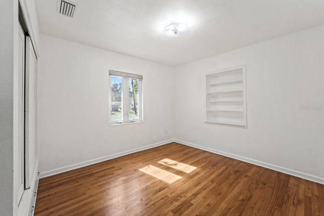 3600 46th St N, Saint Petersburg, FL 33713 - empty room featuring built in shelves, baseboards, wood finished floors, and visible vents
