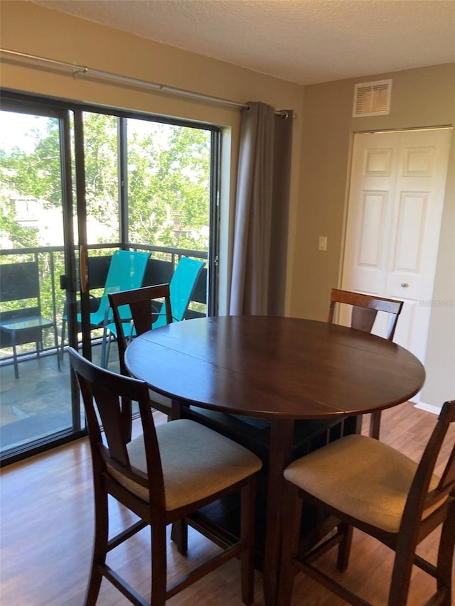 dining space featuring wood finished floors, plenty of natural light, and a textured ceiling