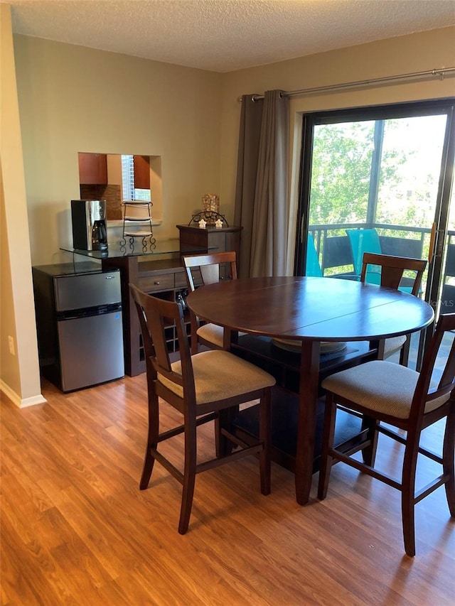 dining area with light wood-style floors, plenty of natural light, and a textured ceiling