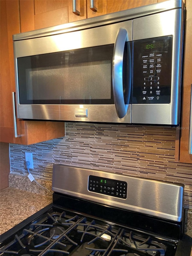 kitchen view of stainless steel appliances, decorative backsplash, and brown cabinets