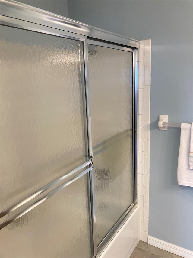 full bathroom with shower / bath combination with glass door and baseboards