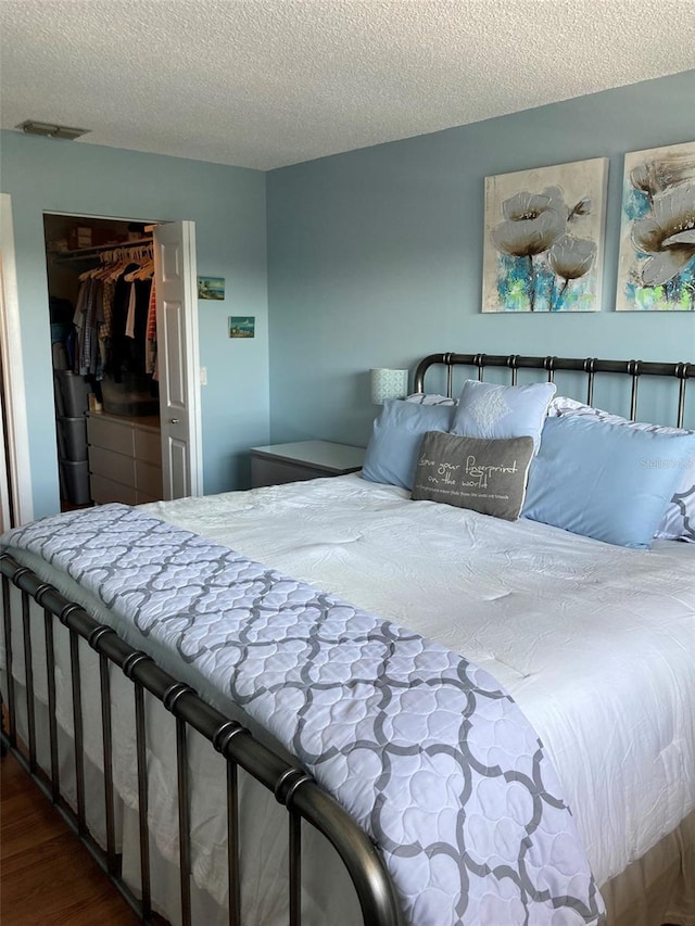 bedroom featuring wood finished floors, a textured ceiling, and a closet