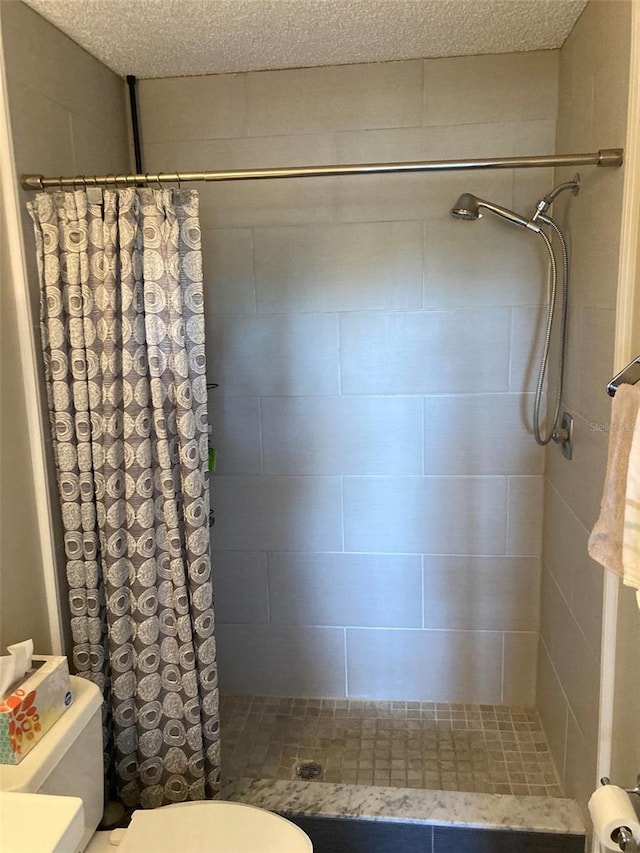 full bathroom with a tile shower and toilet