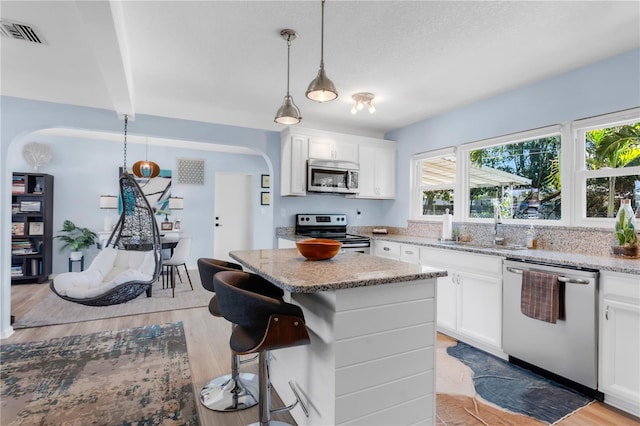 kitchen with light stone counters, visible vents, a sink, light wood-style flooring, and appliances with stainless steel finishes