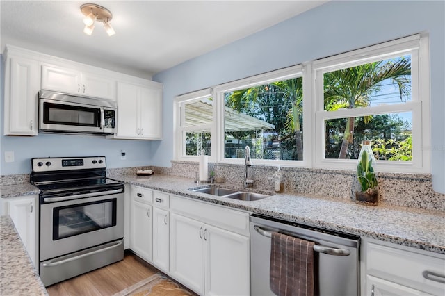 kitchen with a wealth of natural light, a sink, white cabinetry, and appliances with stainless steel finishes