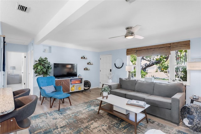 living area with baseboards, wood finished floors, visible vents, and a ceiling fan