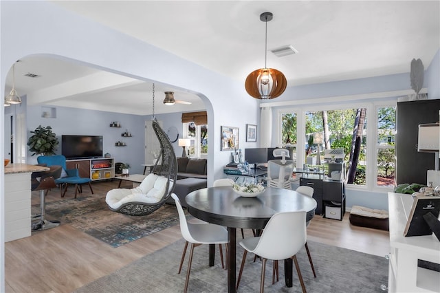 dining area with arched walkways, wood finished floors, and visible vents