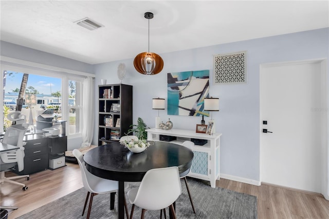 dining room with light wood-style flooring, visible vents, and baseboards