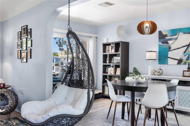 dining space with arched walkways, wood finished floors, and visible vents
