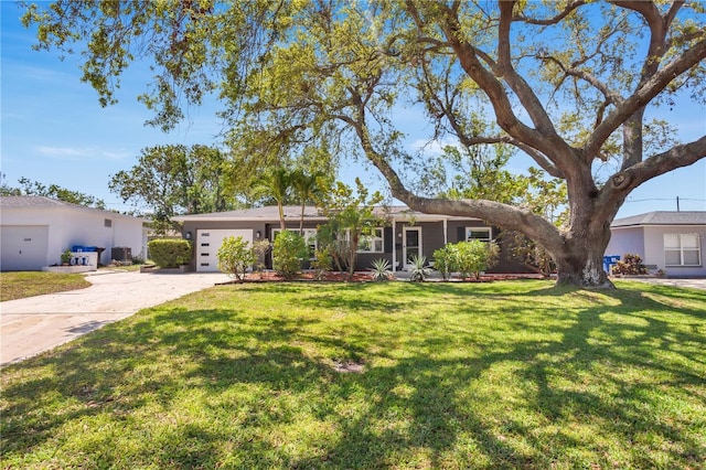 ranch-style home featuring central AC unit, driveway, a front yard, and a garage