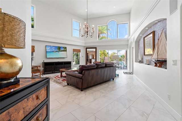 living area featuring a towering ceiling, baseboards, marble finish floor, and a notable chandelier