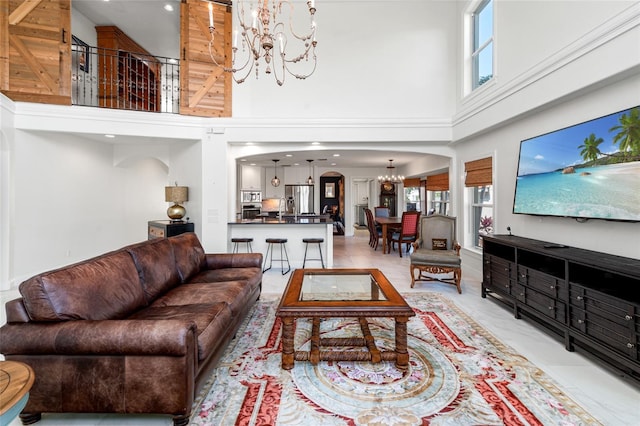 living room featuring a wealth of natural light, a high ceiling, arched walkways, and a chandelier