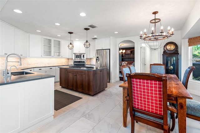 kitchen with a sink, marble finish floor, appliances with stainless steel finishes, a notable chandelier, and visible vents