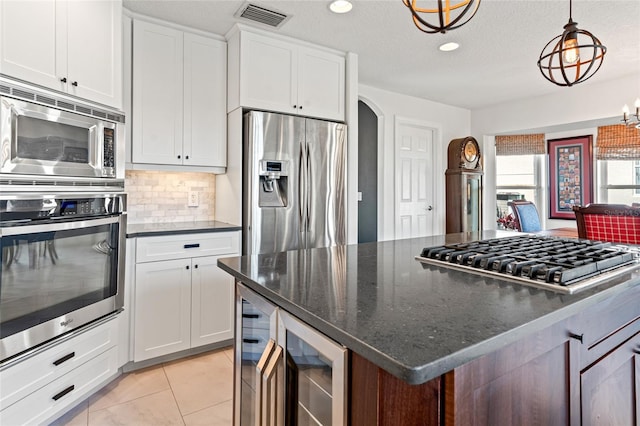 kitchen with wine cooler, visible vents, arched walkways, tasteful backsplash, and appliances with stainless steel finishes