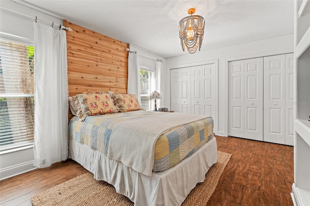 bedroom with wood finished floors, a chandelier, and multiple closets