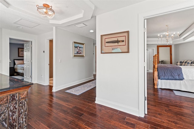 corridor with dark wood finished floors, visible vents, baseboards, and an inviting chandelier
