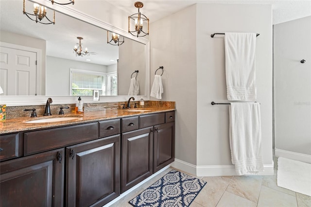 full bathroom featuring baseboards, a sink, a notable chandelier, and double vanity