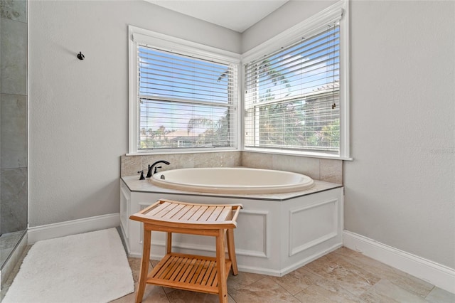 bathroom with a garden tub and baseboards