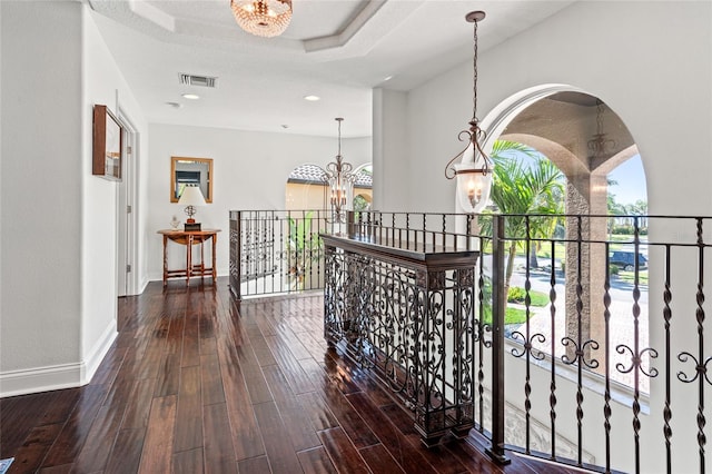 hallway featuring hardwood / wood-style flooring, visible vents, a wealth of natural light, and a notable chandelier