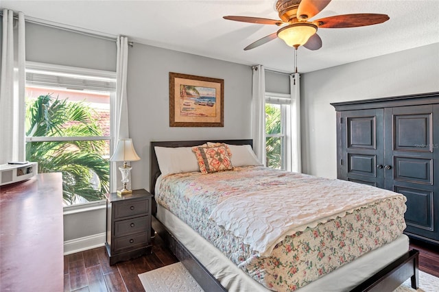 bedroom with ceiling fan, baseboards, and dark wood-style flooring
