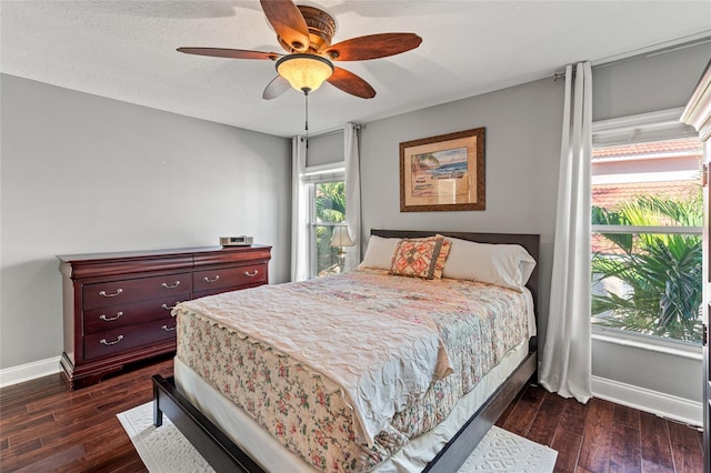 bedroom with ceiling fan, baseboards, and dark wood-style floors