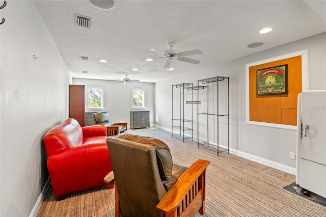 living room with ceiling fan, visible vents, a textured ceiling, and light colored carpet