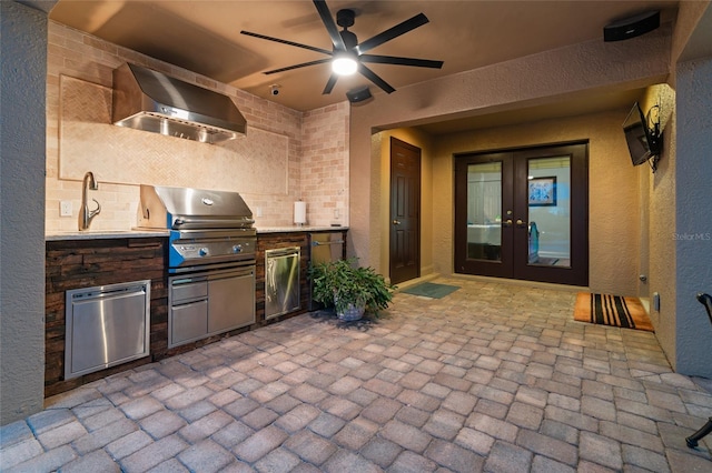 view of patio with french doors, a sink, a grill, a ceiling fan, and an outdoor kitchen