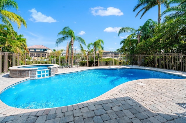 view of pool featuring fence, a patio area, and a pool with connected hot tub