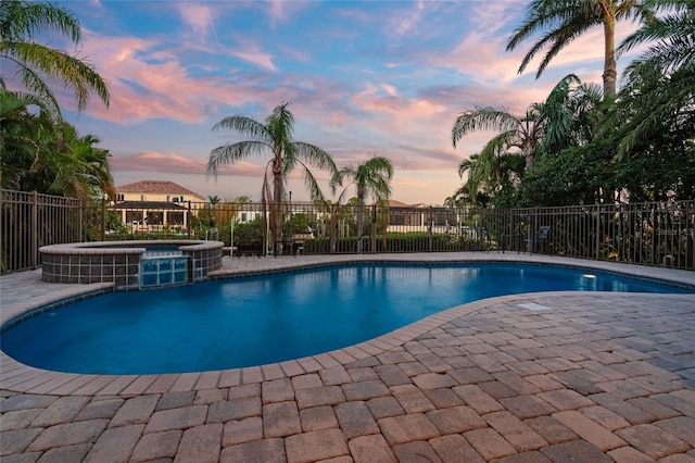 view of swimming pool featuring fence, a pool with connected hot tub, and a patio