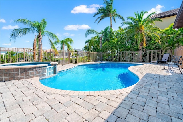 view of swimming pool featuring a patio area, a pool with connected hot tub, and fence