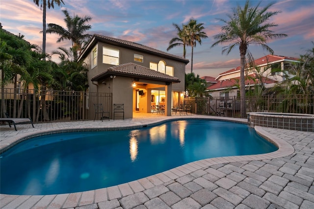 view of swimming pool with a fenced backyard, a pool with connected hot tub, and a patio
