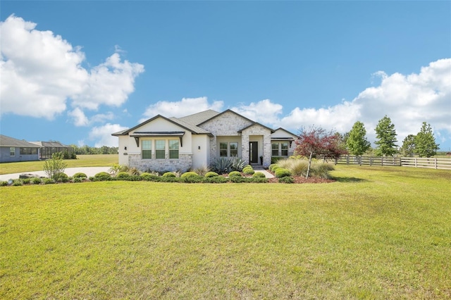 view of front facade with stone siding, a front lawn, and fence