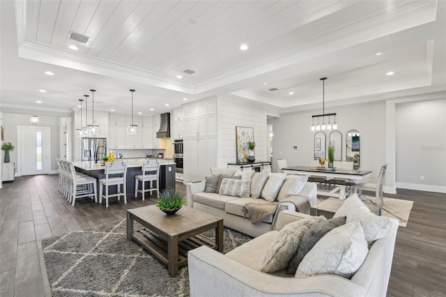 living room featuring a tray ceiling, baseboards, dark wood-style flooring, visible vents, and recessed lighting