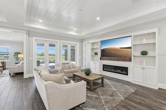 living room with french doors, a tray ceiling, dark wood finished floors, a glass covered fireplace, and crown molding