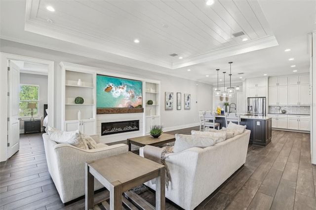 living room featuring a tray ceiling, dark wood-style flooring, visible vents, recessed lighting, and crown molding