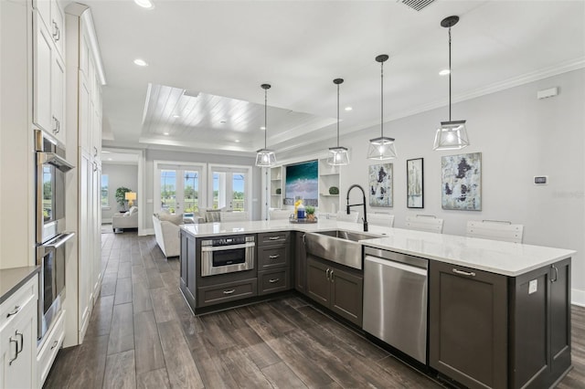 kitchen with a sink, ornamental molding, open floor plan, white cabinets, and appliances with stainless steel finishes