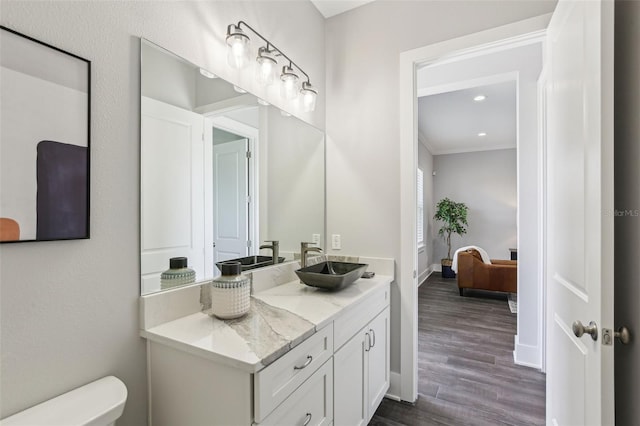 bathroom with recessed lighting, wood finished floors, toilet, vanity, and ornamental molding