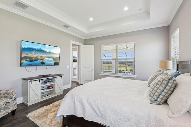 bedroom with dark wood-type flooring, a raised ceiling, visible vents, and ornamental molding