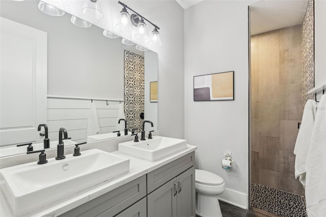 full bathroom featuring double vanity, a shower stall, toilet, and a sink