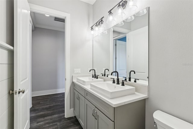bathroom with double vanity, visible vents, toilet, and a sink