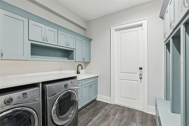 laundry area featuring a sink, cabinet space, baseboards, dark wood-type flooring, and independent washer and dryer