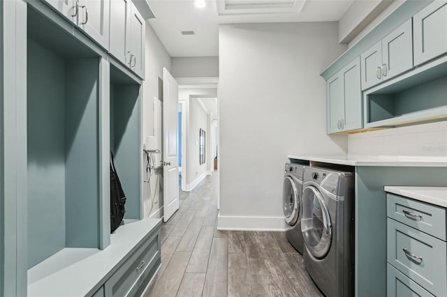 clothes washing area with dark wood-style floors, washing machine and dryer, baseboards, visible vents, and cabinet space