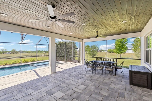 view of patio with a lanai, a pool with connected hot tub, outdoor dining space, and a ceiling fan