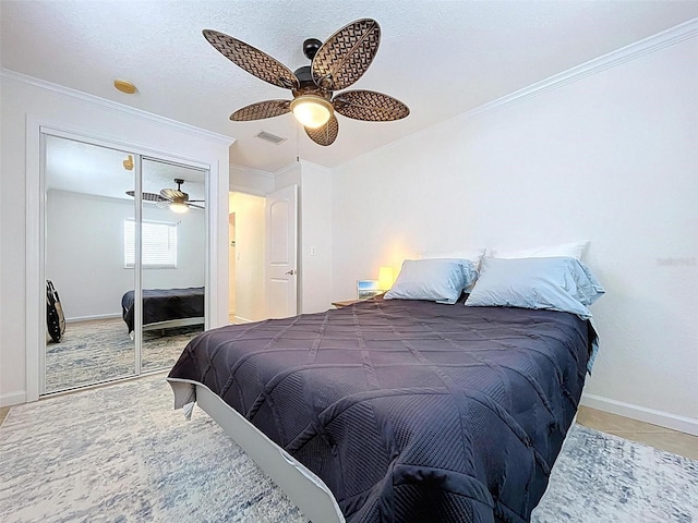bedroom with ceiling fan, visible vents, crown molding, baseboards, and a closet