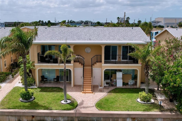 back of house with a patio, a yard, stucco siding, and a balcony