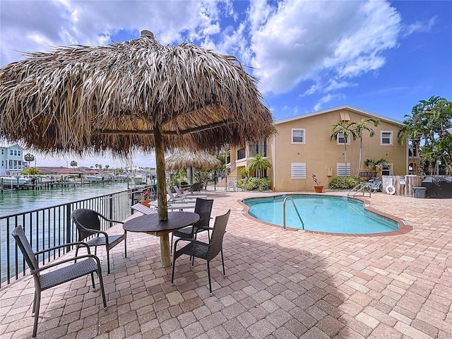 pool with a water view, a patio, and fence